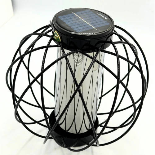 Ażurowa obudowa otacza przezroczysty cylinder z wkładem solarnym. Na zdjęciu dobrze widać kształt znicza oraz układ metalowych prętów.
